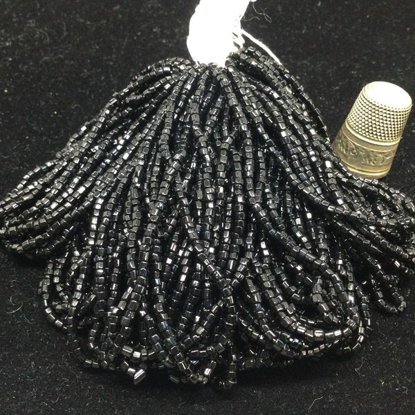 80g de perles noires, en verre, anciennes sur fil. Vintage glass seed beads on a cotton thread.