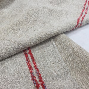 May include: Two pieces of off-white linen fabric with red stripes. The fabric is folded in half and the red stripes are visible on both sides.