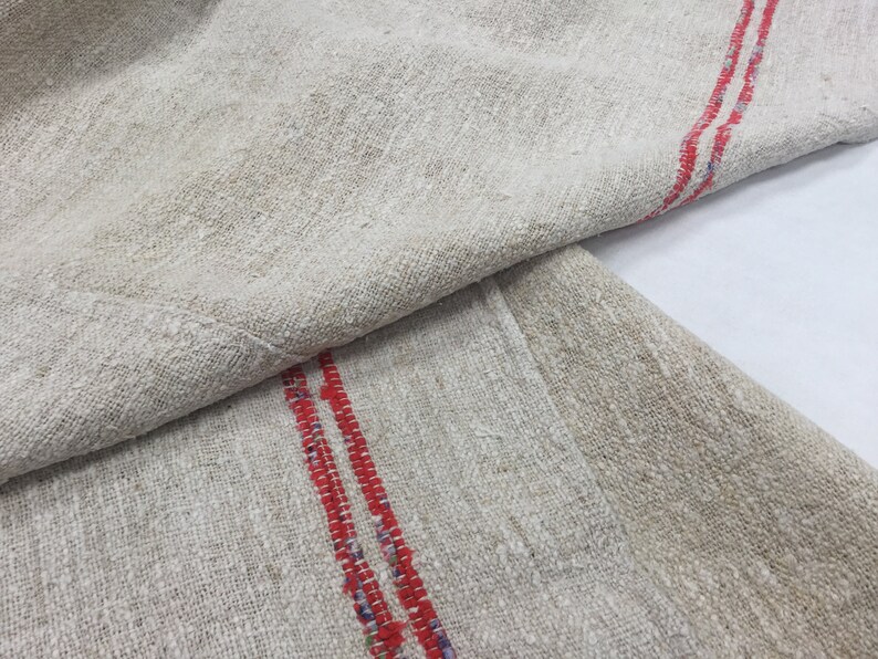 May include: Two pieces of off-white linen fabric with red stripes. The fabric is folded in half and the red stripes are visible on both sides.