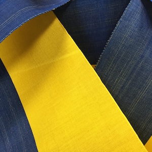 Peut inclure: Gros plan sur un tissu bleu et jaune avec une texture tissée. Le tissu est plié de manière à montrer les différentes couleurs.