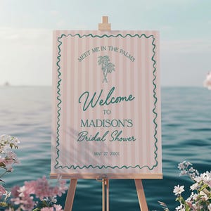 May include: A pink and white striped sign with a green palm tree design. The sign reads "Meet me in the palms, Welcome to Madison's Bridal Shower, May 27, 20XX".