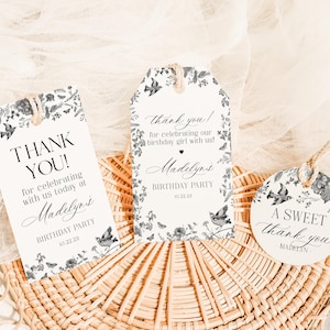 May include: Three decorative tags with floral and bird illustrations. The tags read "Thank You!" and "A Sweet Thank You" with the name "Madelyn's" and the date "10.22.23" printed on them. The tags are tied with twine.