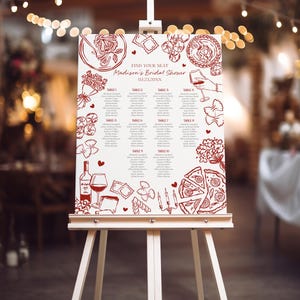 Puede incluir: Un caballete blanco exhibe un plano de asientos para la despedida de soltera de Madison. El gráfico presenta ilustraciones rojas de pasta, pizza, vino y flores. El texto "Find Your Seat" y la fecha están en la parte superior. Los nombres están listados debajo de los números de mesa.