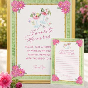 May include: A framed sign and card set with a floral design. The sign reads "Favorite Memories" with a watercolor illustration of cocktails. The card says "Favorite Memories with the Bride to Be". Pink flowers and green accents.