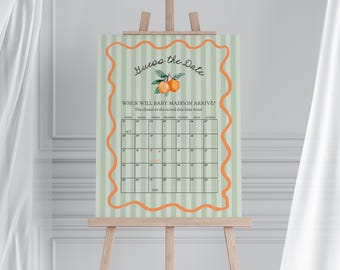 May include: A green and white striped card with an orange citrus fruit design. The card says "Guess the Date" and has a calendar with the month of October and November. The text says "When will baby Madison arrive? The closest to the actual due date wins!"