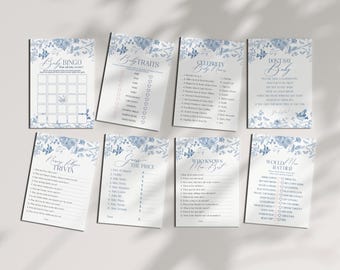 May include: A set of printable baby shower game cards with a blue and white floral design. The cards include games like Baby Bingo, Baby Traits, Celebrity Baby Names, Don't Say Baby, Nursery Rhyme Trivia, Guess the Price, Who Knows Mom Best, and Would Mom Rather.