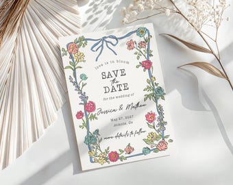May include: Save the date card with a floral border and blue ribbon. The text reads "love is in bloom, save the date, for the wedding of Jessica & Mathew, May 27, 2027, Atlanta, Ga, more details to follow."