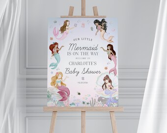 May include: A baby shower sign featuring watercolor illustrations of mermaids with pink and teal tails. The sign reads "Our Little Mermaid is on the Way" and welcomes guests to Charlotte's baby shower, dated 02.23.2026.