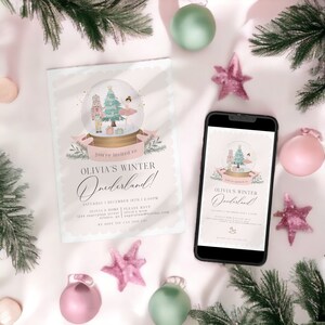 May include: A light pink invitation and a smartphone displaying the same design. The invitation features a snow globe illustration with a Christmas tree, ballerina, and nutcracker. Text reads "Olivia's Winter Onederland!" with event details.