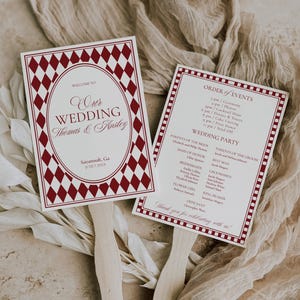 May include: Two wedding fan programs with burgundy diamond patterns and text. One says "Welcome to Our Wedding Thomas & Ansley" and the other lists the order of events and wedding party details. Wooden handles are attached.