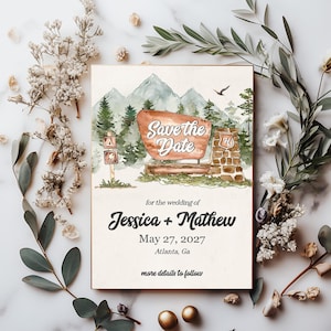May include: Save the Date wedding invitation with a watercolor illustration of a mountain landscape, a wooden sign with the text "Save the Date", and a stone structure with the number "76" on it. The text below the illustration reads "for the wedding of Jessica + Mathew, May 27, 2027, Atlanta, Ga, more details to follow."