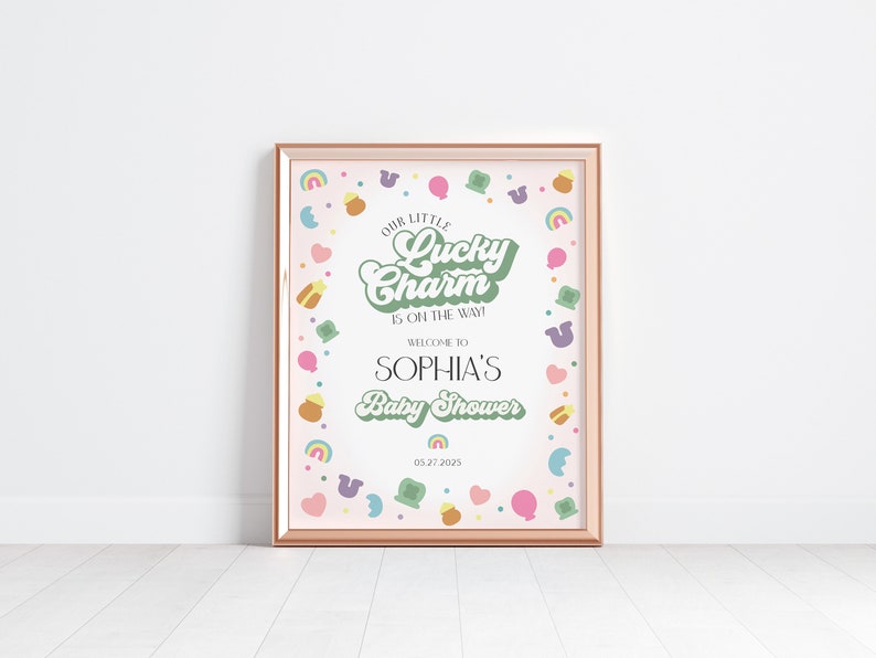 May include: A pink and green baby shower sign with a gold frame. The sign reads "Our Little Lucky Charm is on the way!" and "Welcome to Sophia's Baby Shower" with the date "05272025". The sign is decorated with a border of green shamrocks, rainbows, and gold coins.
