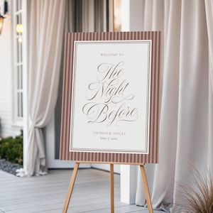 Könnte beinhalten: Ein Willkommensschild auf einer Holzstaffelei. Das Schild zeigt die Worte "Welcome to The Night Before" in eleganter Schrift auf cremefarbenem Hintergrund. Es hat einen braunen Rahmen mit vertikalen Streifen. Das Schild ist für Thomas & Ansley, 7. Juni 20xx.