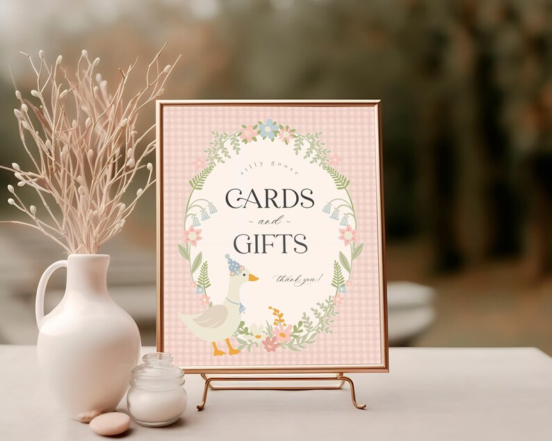 May include: A pink and white gingham sign with a floral border and a cute duck illustration. The sign reads "Cards and Gifts, Thank you!"