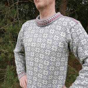 May include: A gray and white patterned sweater with red and white trim around the neck, cuffs, and hem.