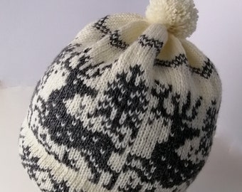 May include: White knitted hat with a black and white geometric pattern and a white pom pom on top.