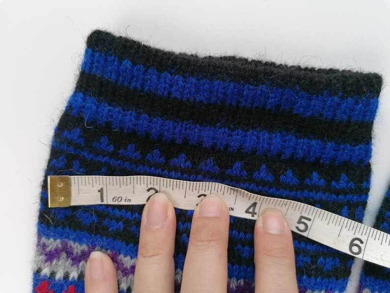 May include: A close-up of a blue and black striped knitted sock with a measuring tape across it. The tape reads "60 in" and shows measurements in inches.