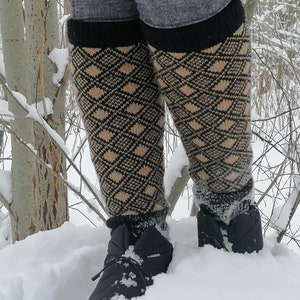 Könnte beinhalten: Ein Paar schwarze und braune, gemusterte Kniestrümpfe mit schwarzen Bündchen. Die Socken werden von einer Person getragen, die im Schnee steht.
