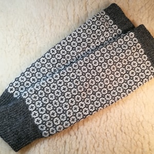 May include: A pair of gray and white knitted leg warmers with a geometric pattern. The leg warmers are made of a soft, warm material and are perfect for keeping your legs warm in the winter.