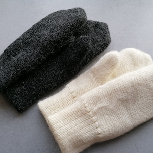May include: A pair of knitted mittens, one black and one white.