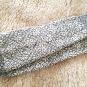 May include: Gray and white knitted leg warmers with a geometric pattern.