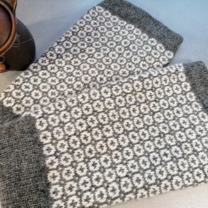 May include: A pair of gray and white knitted arm warmers with a geometric pattern.