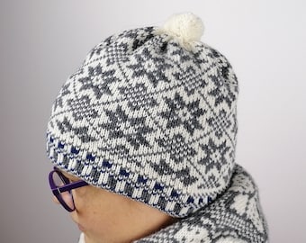 May include: A white and gray knitted hat with a pom-pom on top. The hat has a blue and white trim around the bottom.