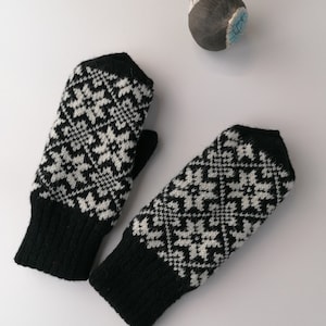 May include: A pair of black and white knit fingerless gloves with a geometric pattern.