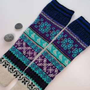 May include: Pair of knitted leg warmers with a colorful geometric pattern in shades of blue, purple, white, and black. The leg warmers are made of a soft, warm material and are perfect for keeping your legs warm in the winter.