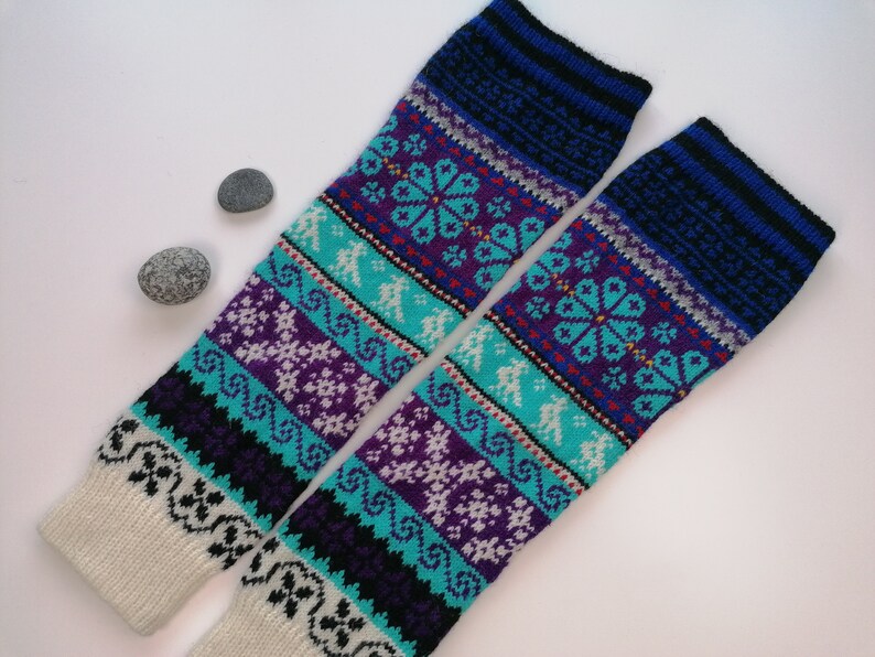 May include: Pair of knitted leg warmers with a colorful geometric pattern in shades of blue, purple, white, and black. The leg warmers are made of a soft, warm material and are perfect for keeping your legs warm in the winter.