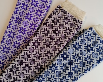 May include: Three pairs of knitted leg warmers with a white background and a geometric pattern in shades of purple, blue, and black.