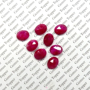 Puede incluir: Ocho piedras preciosas rosadas de forma ovalada y facetadas. Las piedras preciosas están dispuestas en una fila, con la piedra más grande en el centro.