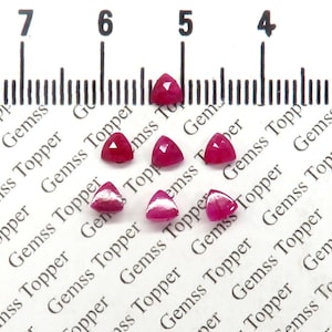 Könnte beinhalten: Sieben rosa dreieckige Edelsteine, die jeweils etwa 5 mm messen, sind auf einer weißen Oberfläche mit einem Lineal im Hintergrund angeordnet. Das Lineal ist mit den Zahlen 4, 5, 6 und 7 gekennzeichnet.