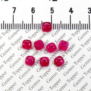 Puede incluir: Nueve piedras preciosas cabujón de forma cuadrada de color rosa, que miden aproximadamente 5 mm x 7 mm, están esparcidas sobre una superficie blanca con el texto "Gemss Topper" repetido en negro.