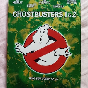 May include: A DVD case with a green background featuring the Ghostbusters logo, a red no ghost sign with a white ghost inside, and the text "Who you gonna call?" The case features the names of the actors Bill Murray, Dan Aykroyd, Harold Ramis, Rick Moranis, and Sigourney Weaver.