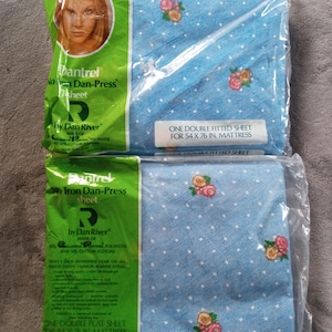 May include: Two packaged Dan River double bed sheets. The sheets are light blue with a white dotted pattern and floral accents. One package reads "One Double Fitted Sheet for 54 x 76 in. Mattress". The other reads "One Double Flat Sheet for 54 x 76 in. Mattress".