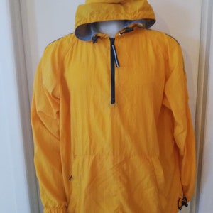 May include: A yellow hooded jacket with black zipper and black and white trim. The jacket has a drawstring at the bottom and a kangaroo pocket.
