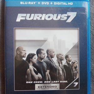 May include: A blue Blu-ray case for the movie "Furious 7." The cover features a group of actors and the text "ONE CREW. ONE LAST RIDE." Includes extended and theatrical versions.