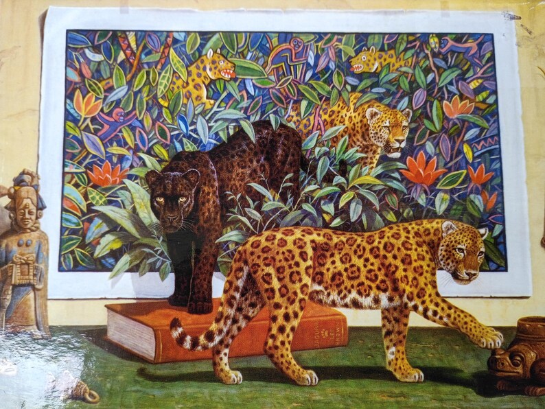 May include: A rectangular print featuring a dense jungle scene with three leopards, one black and two spotted, surrounded by colorful foliage and small monkeys. A large book and a small ceramic figurine are placed in the foreground.