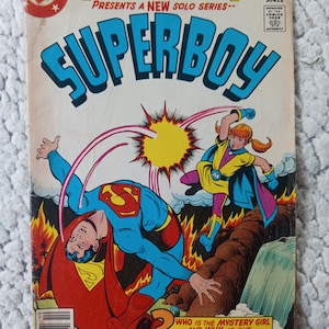 Puede incluir: Una portada de cómic con Superman y una chica misteriosa. La portada es roja, azul y amarilla con el título "SUPERBOY" en letras azules grandes. El texto dice "¿Quién es la chica misteriosa? - ¿Y por qué está reemplazando a Superboy?"