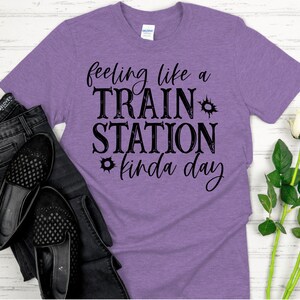 May include: Purple t-shirt with the text "feeling like a TRAIN STATION kinda day" in black.