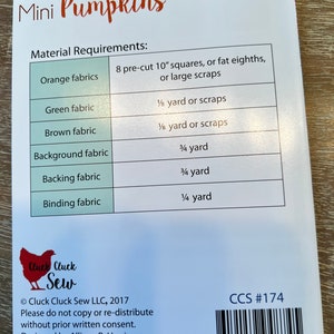 May include: Mini Pumpkins quilting pattern with material requirements listed in a table. The pattern is 23 1/2 inches by 29 inches. The pattern is from Cluck Cluck Sew LLC and includes the copyright year 2017.