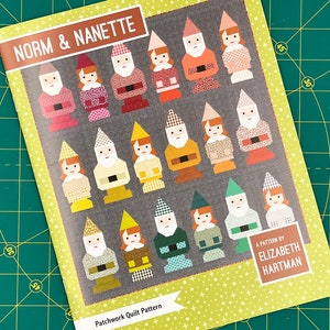 May include: A patchwork quilt pattern booklet titled "Norm & Nanette" by Elizabeth Hartman. The cover features a colorful illustration of 18 gnomes with different colored hats and clothing.