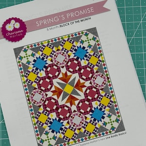 May include: A colorful quilt block pattern with a starburst design in shades of red, yellow, blue, and green. The pattern is titled "Spring's Promise" and is an 8-month block of the month quilt. The quilt is 68 inches by 85 inches.