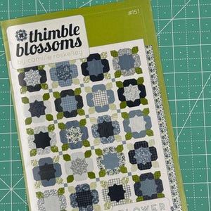 May include: A quilting pattern titled "Flower Girl" by Thimble Blossoms, a fat quarter friendly quilt pattern. The pattern features a green background with a quilt design in shades of blue, green, and white.