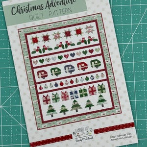 May include: A Christmas Adventure quilt pattern featuring a festive design with a camper, stars, hearts, ornaments, presents, and trees. The pattern is printed on a white background with red and green accents. The pattern is titled "Christmas Adventure" and is by Flamingo Toes, Beverly McCullough.