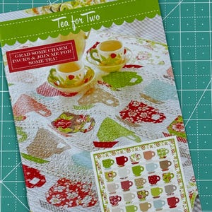 May include: A quilting pattern featuring a teacup design with the text "Tea for Two" and "Grab some charm packs & join me for some tea!"  The pattern includes a grid of teacups in various colors and patterns.