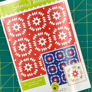May include: A quilt pattern booklet titled "Annie's Wreaths" featuring a red and white star block pattern and a blue and white star block pattern. The text "NO TEMPLATE METHOD!" is printed on a green rectangle. The booklet is from Fig Tree & Co. by Joanna Figueroa.