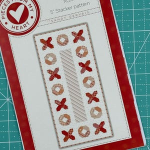 Puede incluir: Un patrón de acolchado titulado "XOX 5' Stacker pattern" de Sandy Gervais. El patrón presenta un diseño rojo y blanco con un patrón repetitivo de X y O.