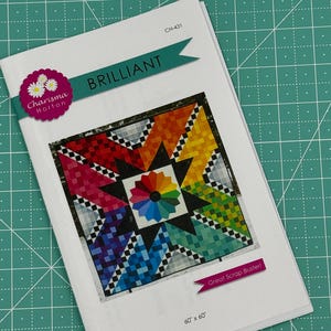 May include: A quilting pattern titled "Brilliant" by Charisma Horton. The pattern features a colorful quilt design with a star in the center. The quilt is 60 inches by 60 inches and is described as a "Great Scrap Buster!"